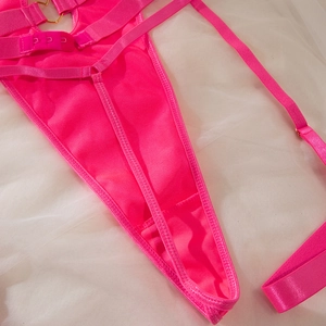 Detail of rose pink bodysuit featuring adjustable straps and gold metal ring connectors