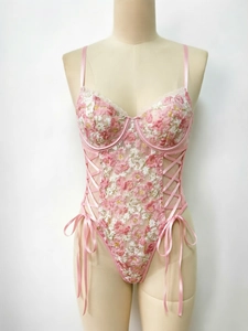 Detailed embroidery of pink flowers on a lace bodysuit with side bow accents