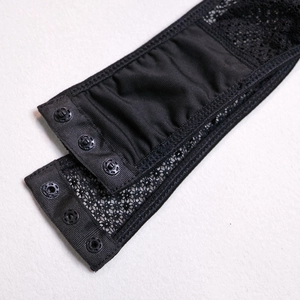 Detail view of black fishnet bodysuit featuring lace trim and three-button crotch snap closure