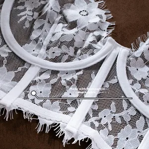 Detailed view of white eyelash lace embroidery and sheer mesh fabric on a corset bra