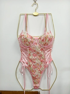 Detailed view of pink floral embroidery and side lace-up ribbons on mesh bodysuit