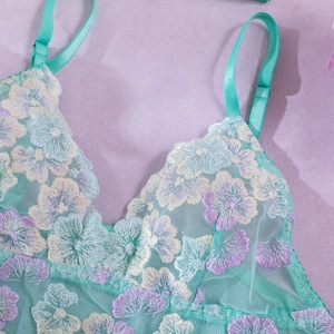 Close-up of floral embroidery on mint green lace lingerie with adjustable straps