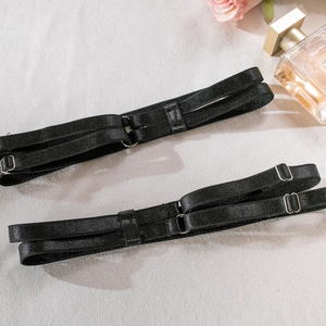 Detail of black elastic garter straps with silver metal adjusters on a textured background