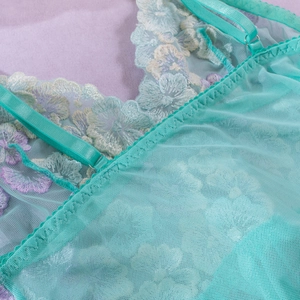 Macro view of mint green mesh lingerie featuring colorful floral lace embroidery details