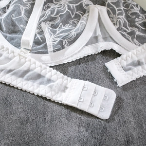 Close-up of white floral lace lingerie with back hook-and-eye closure and mesh wings