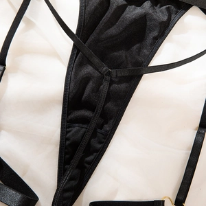 Detailed view of black lingerie with cross-straps and decorative golden metal rings