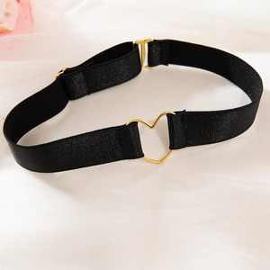 Detail of black elastic choker with a gold heart-shaped buckle on white fabric