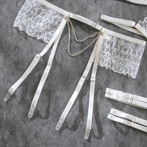 Detail of white lace garter belt with floral embroidery and sparkling rhinestone chains