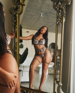 Detailed close-up of a three-piece black lace lingerie set with floral embroidery in a mirror