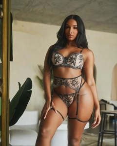 Detailed view of black floral lace embroidery on a beige lingerie set with garter belt