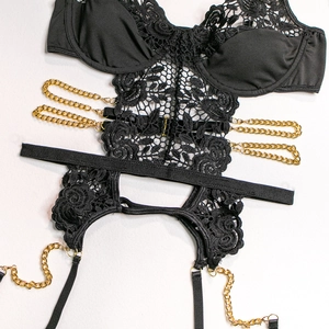 Detail of black lace bodysuit with gold chain straps and floral hollow-out embroidery