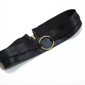 Close-up of black elastic waist strap featuring a decorative gold metal ring detail