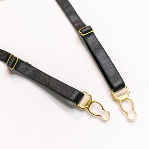 Detail of adjustable black garter straps with premium gold metal hardware and clips