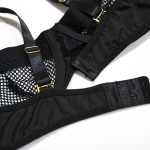 Detail of black mesh bodysuit featuring adjustable gold buckles and three-row back closure