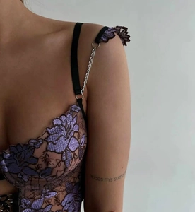 Detail of purple floral embroidery lace with black webbing and silver metal chain straps
