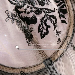 Macro shot of delicate black lace floral embroidery on transparent beige mesh fabric