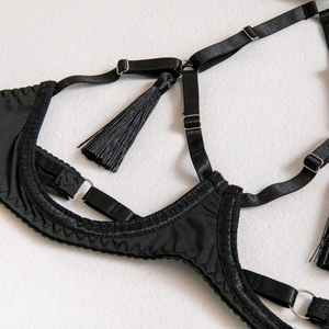 Détail des lanières de lingerie noire avec anneaux argentés et breloque à franges