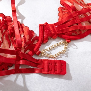 Macro detail of red lace lingerie featuring golden metal chain accents and fine mesh fabric