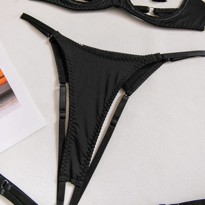 Détail d'un string en satin noir avec bretelles fines réglables et coutures zigzag