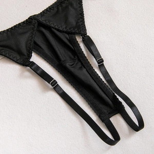 Gros plan d'une jarretière noire avec boucle réglable en métal argenté et coutures
