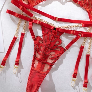 Detail of red lace lingerie with floral embroidery and golden metal chain links