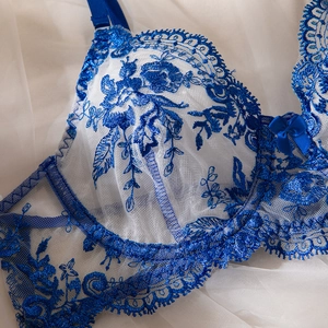 Close-up of blue floral lace embroidery on sheer white mesh fabric of a sexy bodysuit
