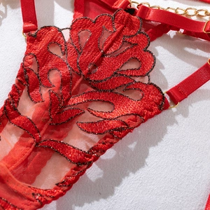 Close-up of red floral embroidery on lace bodysuit with gold chain and metal ring details