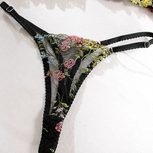 Détails d'un string en tulle noir avec broderies florales et fines bretelles réglables