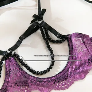 Détail du tissu en dentelle violette transparente avec chaînes de perles et nœud décoratif