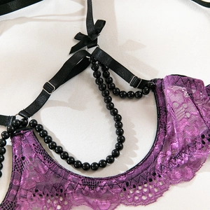 Vue détaillée de la lingerie en dentelle violette avec chaînes de perles noires et nœuds