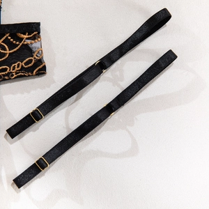 Detail of adjustable black shoulder straps with gold metal buckles and chain embroidery