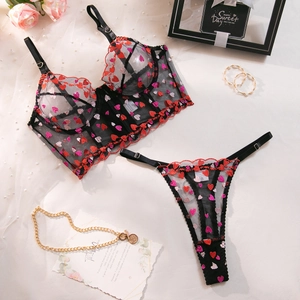 Detailed embroidery of pink hearts on sheer black lace lingerie set with floral props