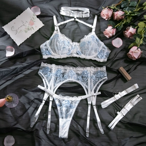 Detailed embroidery of blue roses on a white lace lingerie set with mesh details