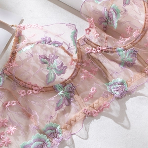 Detail of pink mesh corset bra featuring multi-color floral embroidery and supportive boning