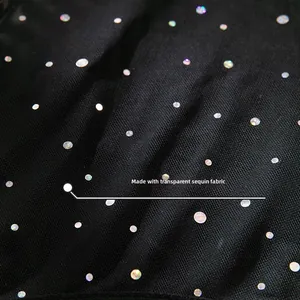 Macro shot of high-gloss iridescent sequins on black mesh fabric for a party dress