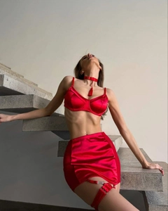 Detail shot of red satin lingerie set featuring a bra, mini skirt, and matching accessories