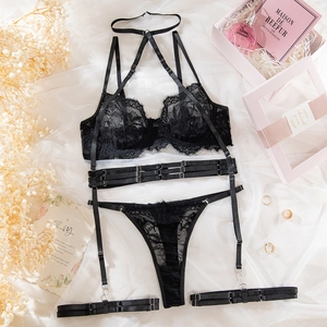 Flat lay of black floral lace lingerie set with garters and decorative perfume accessories