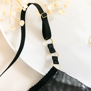 Detailed macro view of black mesh lingerie straps with golden metal ring connectors