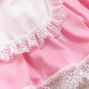 Détail de tissu rose avec bordure en dentelle plissée blanche sur vêtement doux
