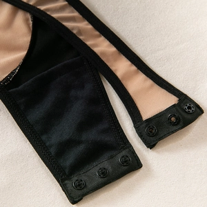 Close-up of bodysuit bottom showing three black metal snap fasteners on mesh fabric