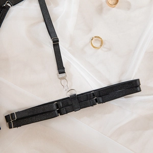 Close-up of black elastic garter straps with silver metal adjusters and clips on white mesh
