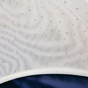Detail des weißen Netzkeids mit schimmernden Pailletten und blauem Seidenfutter