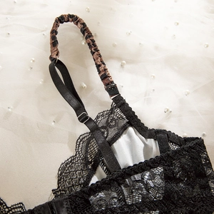 Dettaglio di reggiseno in pizzo nero con spallina leopardata e motivi floreali