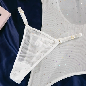 Detail of white mesh lingerie with sequins, metal buckles and washing label on blue satin