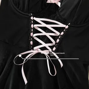 Detail of sheer black mesh fabric with pink ribbon bow and intricate lace trim decor