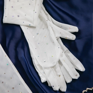 Detailed view of white mesh gloves with sparkling colorful sequins on blue silk fabric