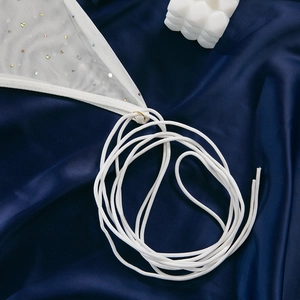 Detailed macro shot of white mesh fabric with sequins, golden rings and elastic ties