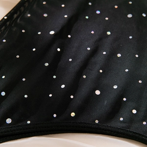 Detailed macro view of holographic sequins on black mesh fabric with clean edge binding