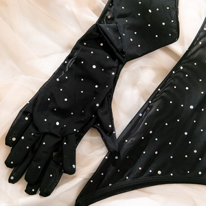 Close-up of black mesh gloves and fabric with colorful iridescent rhinestones on silk