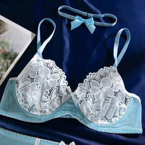 Détail d'un body en dentelle bleu clair avec broderie blanche et nœuds en satin doux